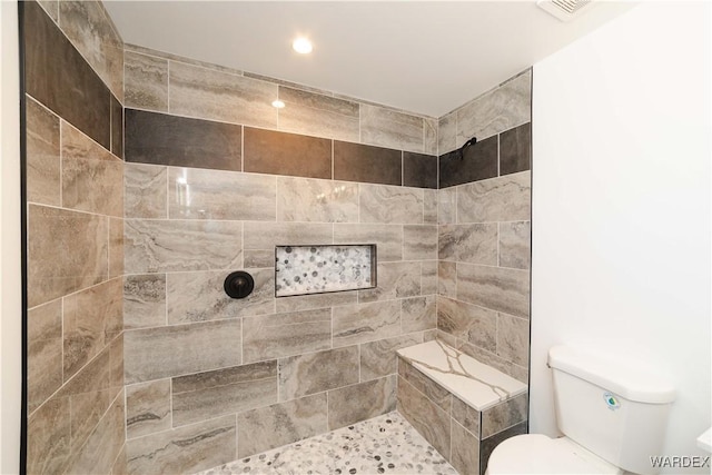 bathroom featuring visible vents, a tile shower, and toilet