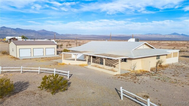 view of front facade featuring a detached garage, a mountain view, and an outdoor structure