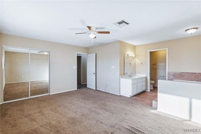 unfurnished bedroom featuring light carpet, visible vents, a sink, and ensuite bathroom