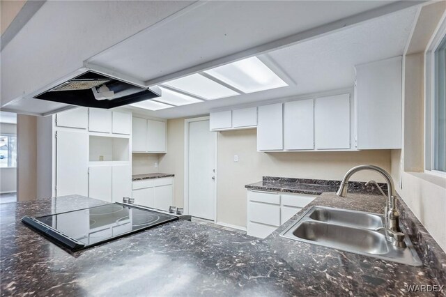 kitchen featuring dark countertops, a sink, black electric cooktop, and white cabinets