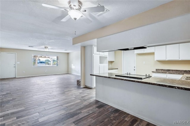 kitchen with white cabinets, dark countertops, wood finished floors, black electric cooktop, and a textured ceiling