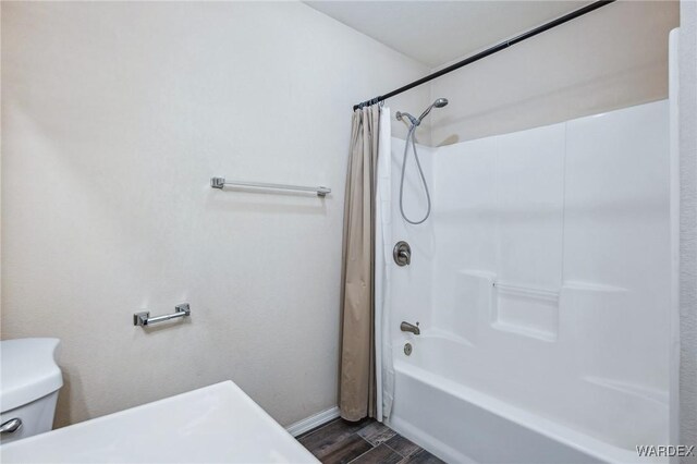 bathroom featuring baseboards, shower / tub combo with curtain, toilet, and wood finished floors