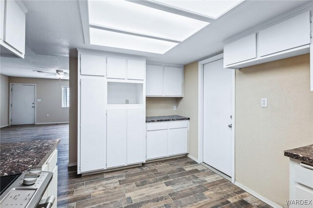 kitchen featuring dark stone countertops, white cabinets, dark wood finished floors, and baseboards