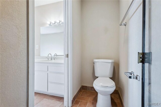 bathroom with toilet, baseboards, vanity, and tile patterned floors