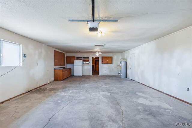 interior space with a garage, a textured ceiling, electric water heater, and unfinished concrete floors