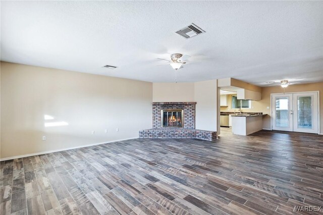 unfurnished living room with ceiling fan, dark wood-type flooring, and visible vents