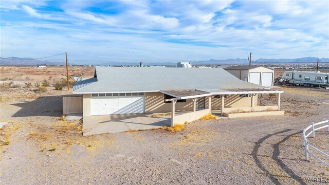 view of front of property with a mountain view, concrete driveway, and an outbuilding