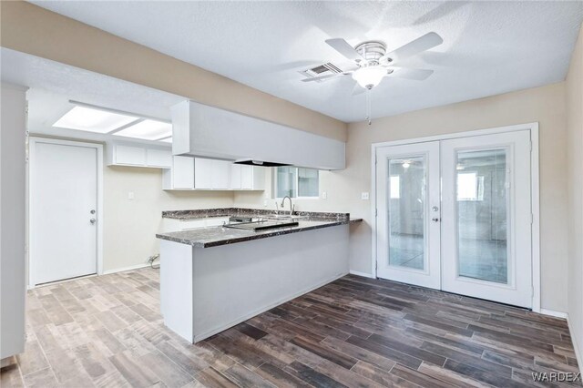 kitchen with white cabinets, dark countertops, dark wood-style floors, a peninsula, and french doors