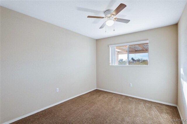 carpeted spare room with ceiling fan and baseboards