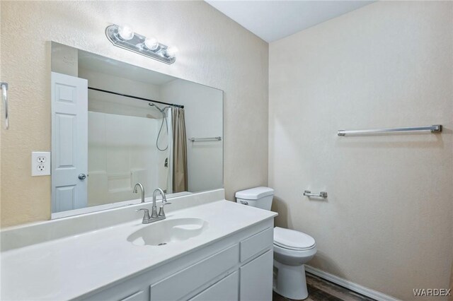 full bath with curtained shower, toilet, vanity, wood finished floors, and baseboards