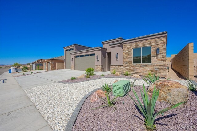 view of front of home featuring a garage, driveway, stone siding, fence, and stucco siding