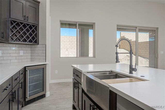 kitchen featuring plenty of natural light, wine cooler, light countertops, and backsplash