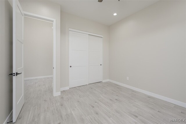 unfurnished bedroom featuring light wood finished floors, a closet, recessed lighting, and baseboards