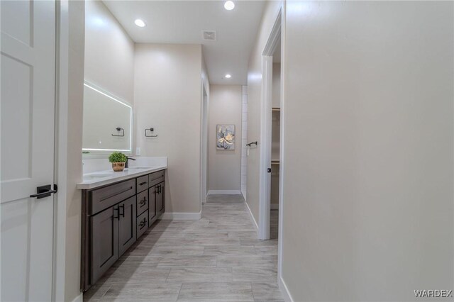 full bathroom featuring a sink, double vanity, a walk in closet, and recessed lighting