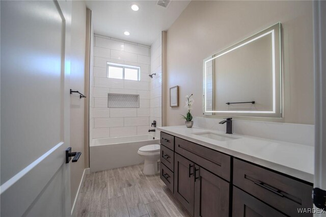 bathroom featuring recessed lighting, bathtub / shower combination, toilet, vanity, and wood finished floors