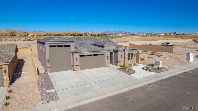 prairie-style home featuring a garage, stone siding, concrete driveway, and stucco siding