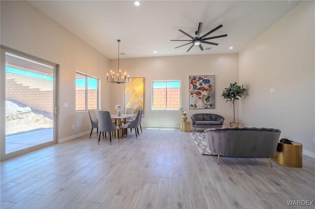 dining space with light wood finished floors, ceiling fan with notable chandelier, baseboards, and recessed lighting