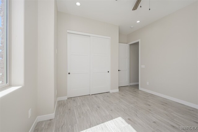 unfurnished bedroom featuring light wood-type flooring, a closet, and baseboards