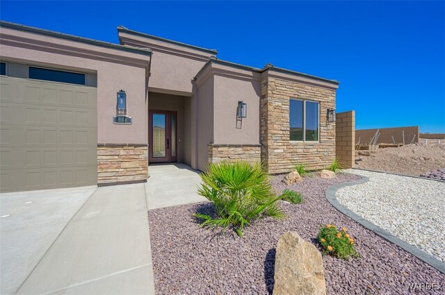 view of front facade with a garage, stone siding, and stucco siding