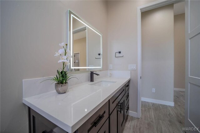 bathroom featuring vanity, baseboards, and wood finished floors