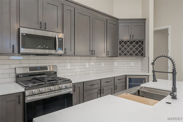 kitchen with decorative backsplash, appliances with stainless steel finishes, light countertops, and a sink