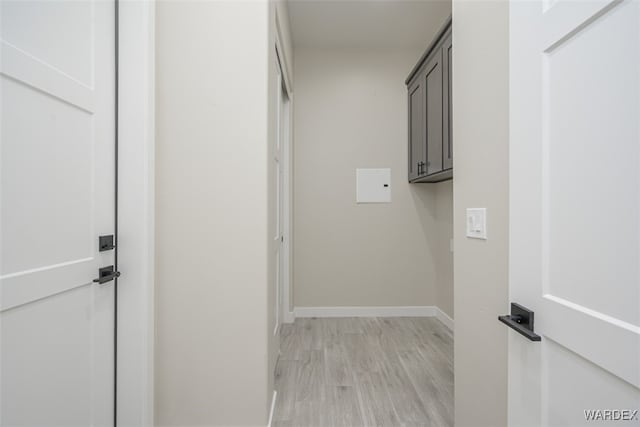 clothes washing area featuring light wood-style flooring and baseboards