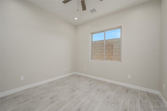 spare room featuring light wood-type flooring, baseboards, visible vents, and a ceiling fan