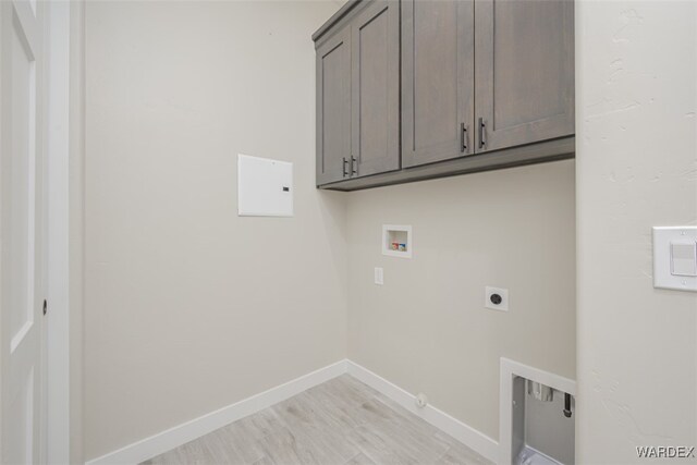 washroom featuring hookup for a washing machine, light wood-style flooring, hookup for an electric dryer, baseboards, and cabinet space