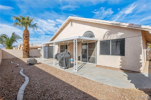 rear view of property with a fenced backyard, a patio, and stucco siding