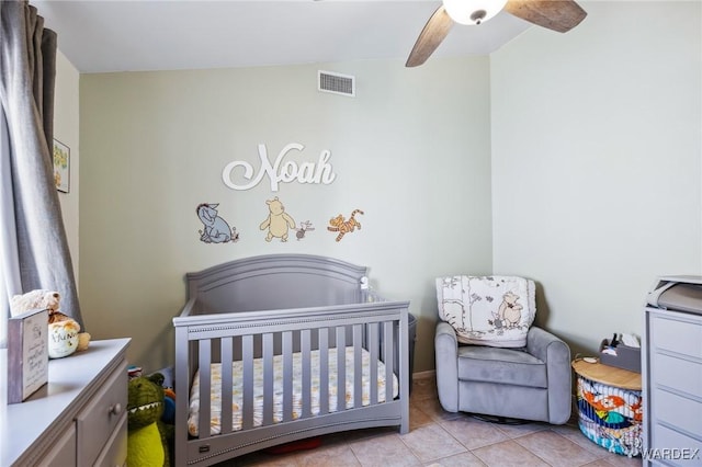 bedroom with a nursery area, light tile patterned floors, visible vents, and a ceiling fan