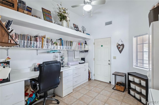 home office with light tile patterned floors, visible vents, a high ceiling, a ceiling fan, and built in study area