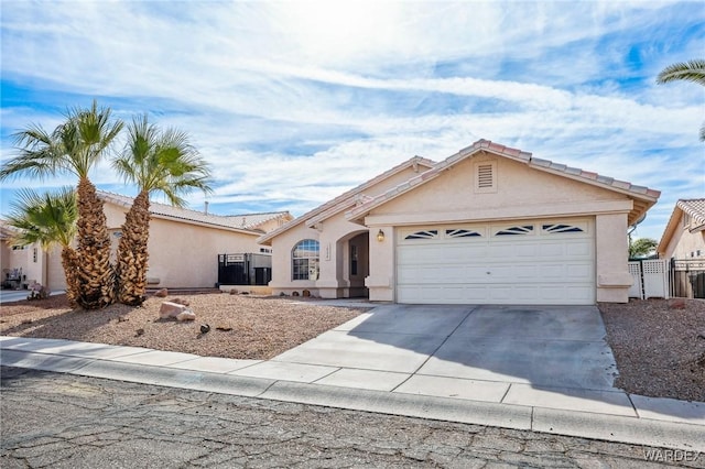 view of front of house with a tile roof, stucco siding, concrete driveway, fence, and a garage