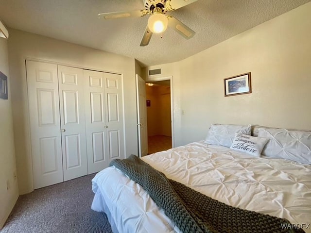 bedroom with a textured ceiling, ceiling fan, visible vents, a closet, and dark carpet