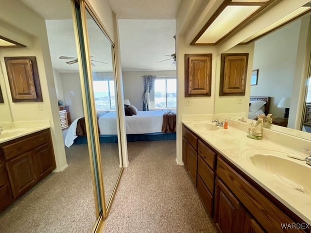 ensuite bathroom with double vanity, a ceiling fan, connected bathroom, carpet floors, and a sink