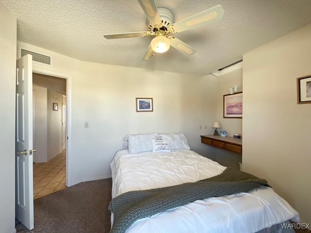 bedroom with a textured ceiling, ceiling fan, visible vents, and tile patterned floors