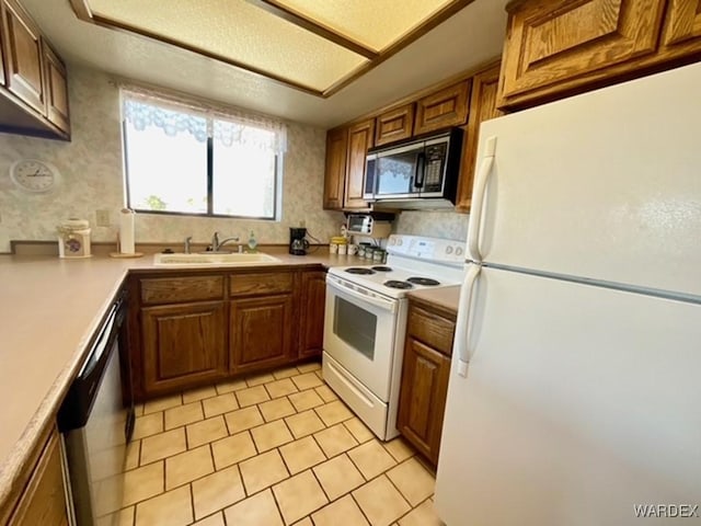 kitchen with light tile patterned floors, appliances with stainless steel finishes, brown cabinets, light countertops, and a sink