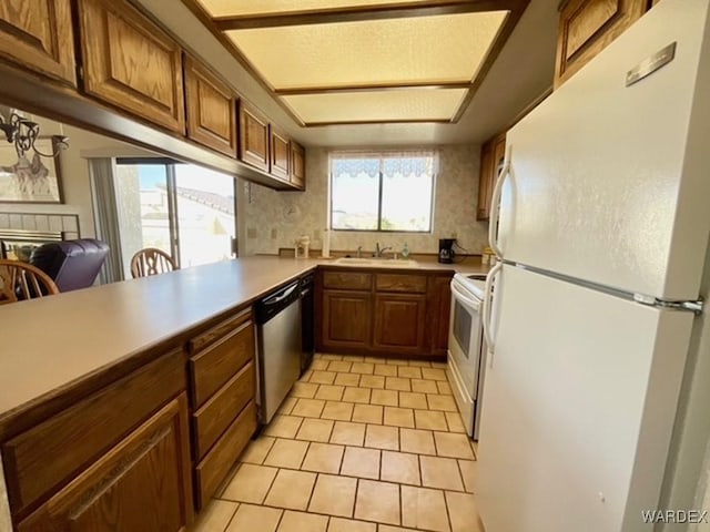 kitchen with brown cabinets, light countertops, light tile patterned flooring, white appliances, and a peninsula