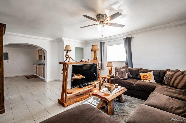 living room featuring ornamental molding, arched walkways, a ceiling fan, and light tile patterned floors