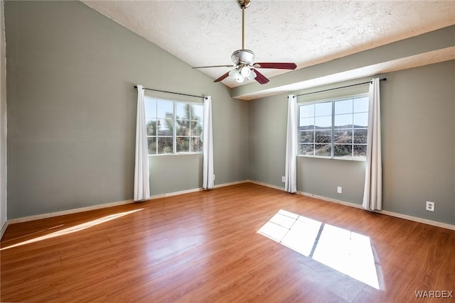 unfurnished room with lofted ceiling, ceiling fan, a textured ceiling, baseboards, and light wood finished floors