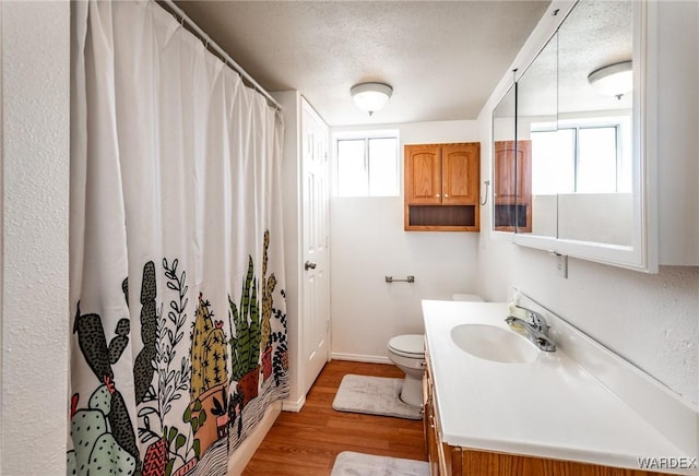 full bath featuring a shower with shower curtain, toilet, a textured ceiling, vanity, and wood finished floors