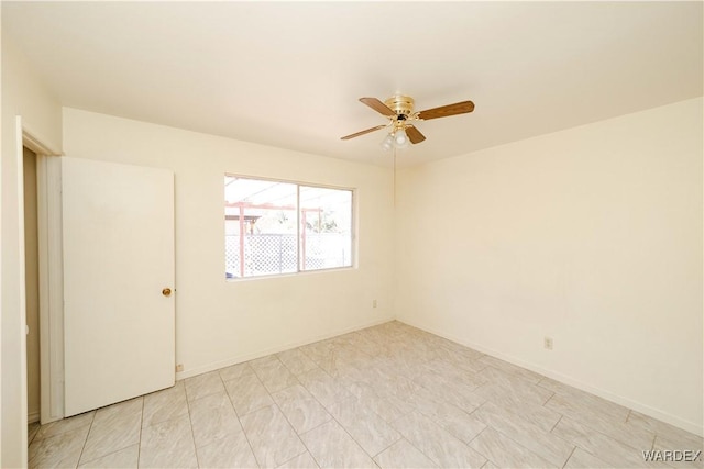 spare room with ceiling fan and baseboards