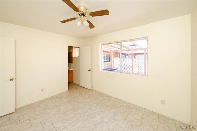 spare room with a ceiling fan and baseboards