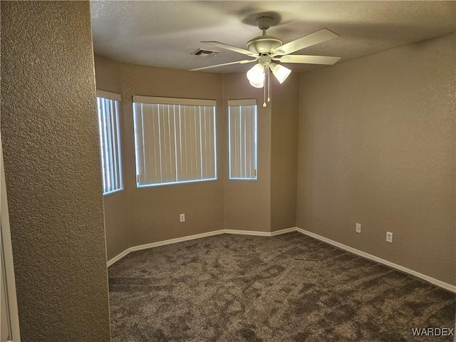 carpeted empty room with visible vents, a textured wall, ceiling fan, a textured ceiling, and baseboards