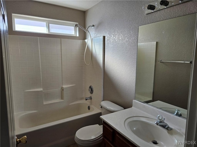 bathroom with toilet, washtub / shower combination, vanity, and a textured wall