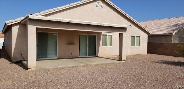 back of property with a tiled roof, a patio, fence, and stucco siding