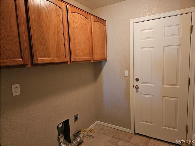 clothes washing area featuring hookup for an electric dryer, cabinet space, baseboards, and light tile patterned flooring