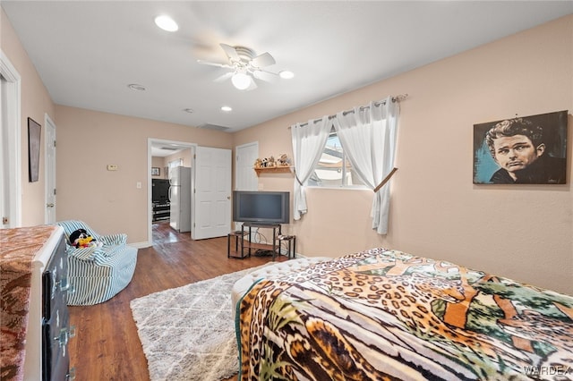 bedroom with wood finished floors, visible vents, a ceiling fan, baseboards, and freestanding refrigerator