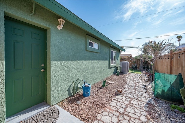 exterior space featuring central air condition unit, fence, and stucco siding