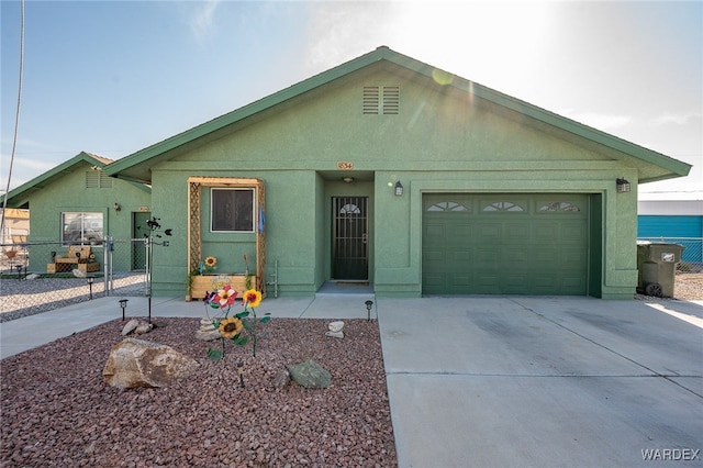 view of front of home with a garage, concrete driveway, fence, and stucco siding