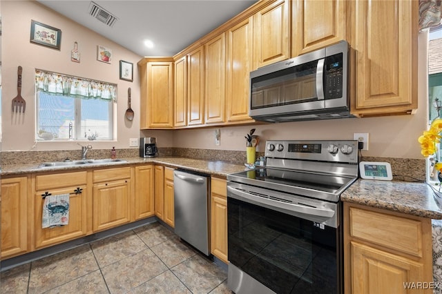 kitchen with light tile patterned floors, visible vents, appliances with stainless steel finishes, a sink, and light stone countertops